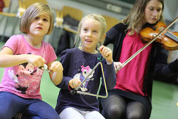 Kinder musizieren mit Triangel und Geige